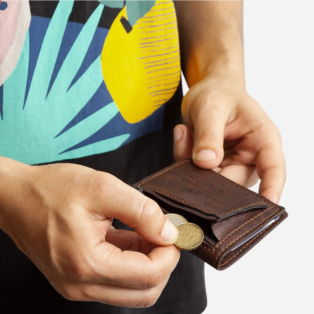 Hand taking coins from the zip pocket of the brown slim cork wallet