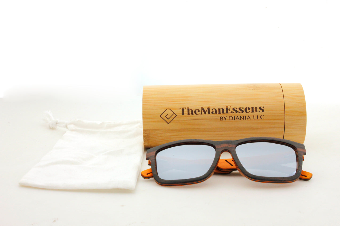 Aitana black laminated wood sunglasses next to cotton bag and in front of bamboo cilincer case