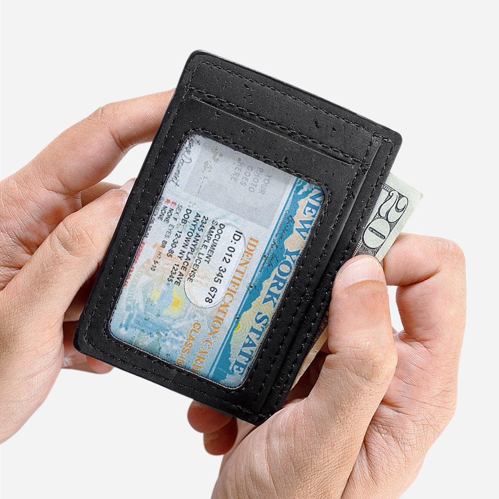 ID Window on the back side of the Cards holder wallet. Hand taking out a 20 dollar bill. Black cork.
