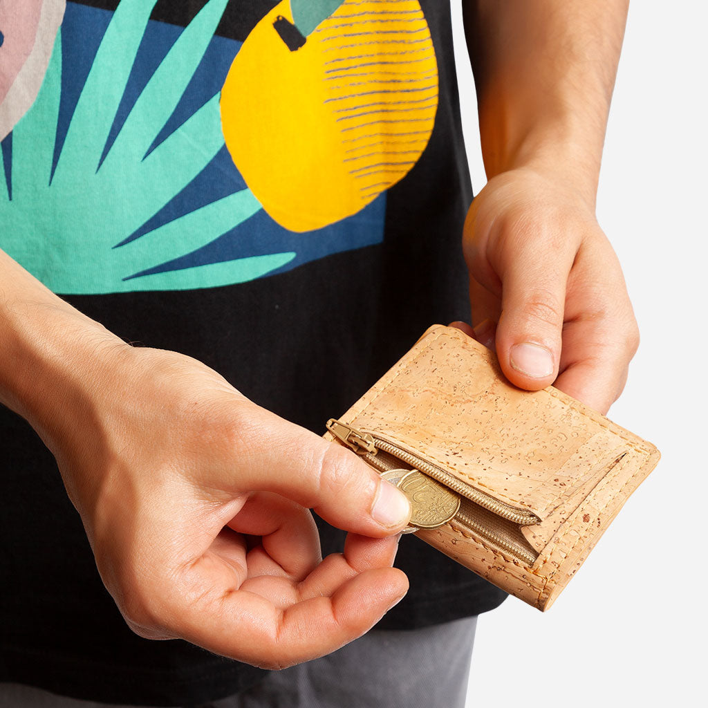 Hand taking out coins from the back Zip coin Pocket of the Slim Wallet. Light Brown Cork.